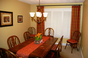 This Dining room has plantation shutters, plaid silk drapes and coordinating chair cushions and table runner.
